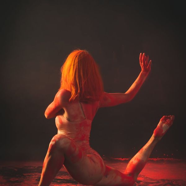 Silhouette of a person in a fluid yoga pose against a dark background.